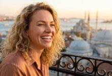 Een gelukkige vrouw met een perfect wit gebit glimlacht vol zelfvertrouwen, met de onscherpe skyline van Istanbul op de achtergrond tijdens een zonsondergang. Het beeld straalt gezondheid, geluk en reizen uit.