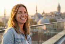 Een persoon met een perfecte, witte glimlach staat buiten, met op de onscherpe achtergrond een zonnig uitzicht op de skyline van Istanbul, Turkije. Dit beeldt het concept van succesvol tandheelkundig toerisme uit.