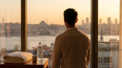 Een man kijkt vanuit een moderne, luxe kamer uit over de skyline van Istanbul bij zonsopgang, wat de combinatie van een medische reis en een vakantie in Turkije symboliseert.